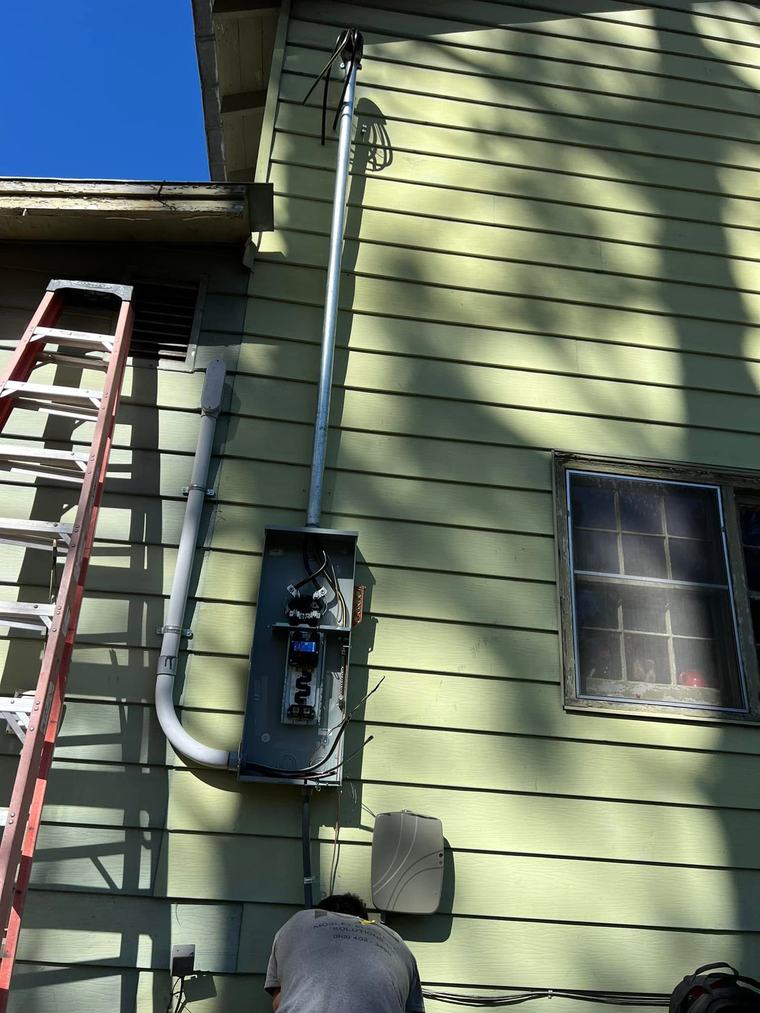 Meter base and panel mounted on an exterior wall with a ladder alongside