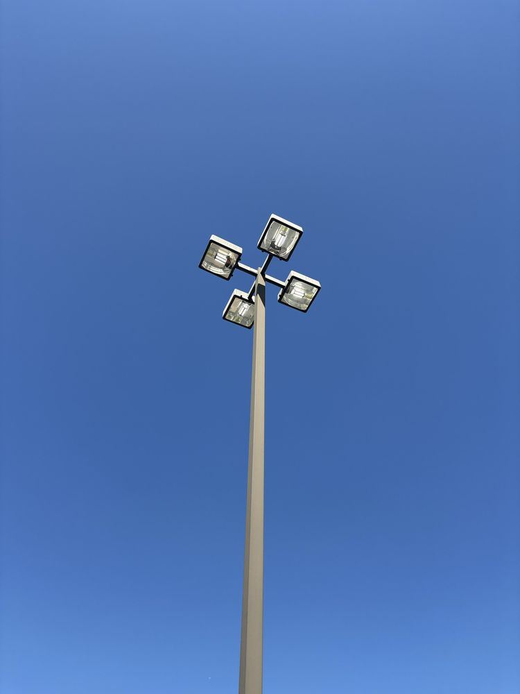 Four-head parking lot light pole against a clear sky